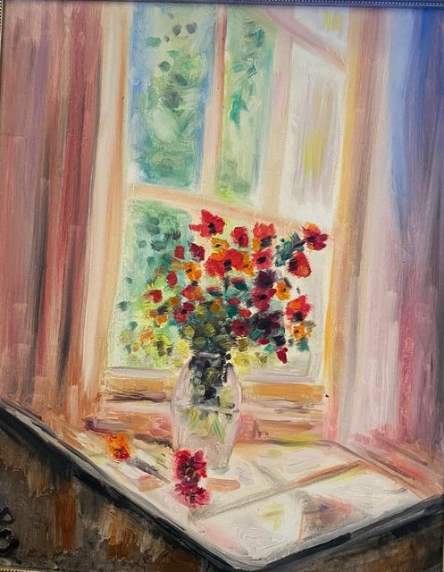 Red flowers in a glass vase before a sunlit window